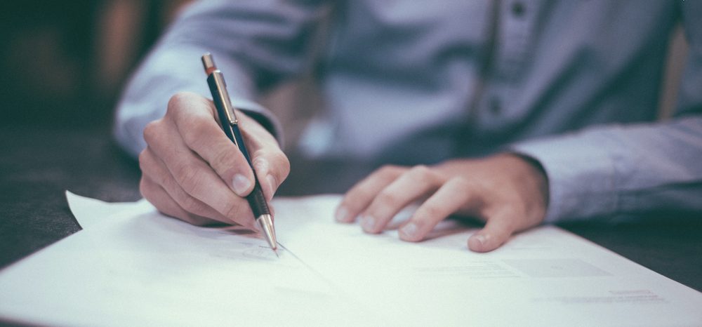 Man holding pencil, writing on paper. Are tax credits refundable? Runey & Associates Wealth Management.